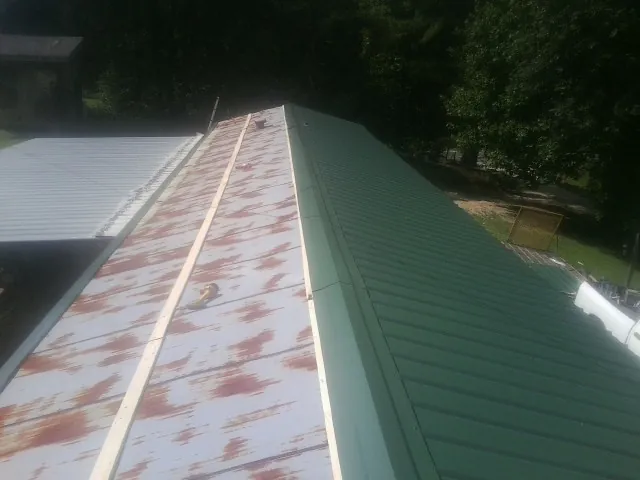 Old rusted panels beside newly installed green metal roofing — Wind Damage Roof Repair by Roofing Brothers in Cache Junction